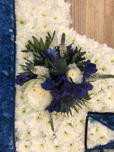 Caravan-shaped funeral tribute made with white chrysanthemum, sprayed detailing, and laminated accents, finished with optional mixed floral focal in chosen colours, measuring approximately 89cm x 51cm.