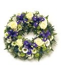 Loose funeral wreath with purple, white, and lime green seasonal flowers, symbolising remembrance and love.